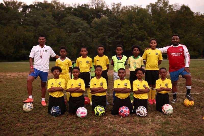 The Henos Soccer Academy squad posed on the field with their coaches