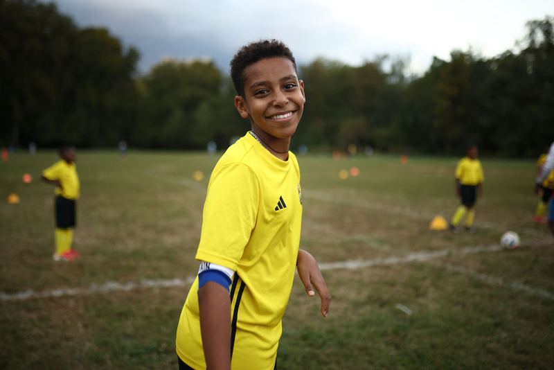 A smiling player in the yellow Henos kit